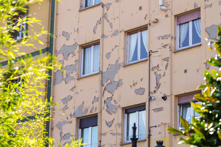 Damaged peeling paint on the wall of a residential building on a city streetの写真素材