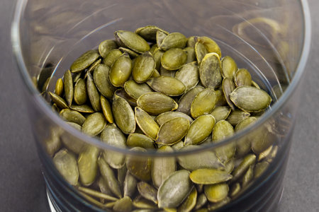 Green organic peeled pumpkin seeds in glass container close upの写真素材