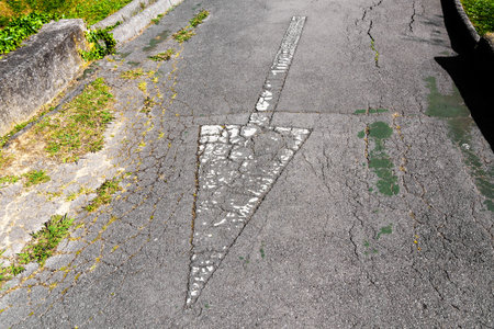 Reverse direction arrow on a weathered asphalt road close upの写真素材