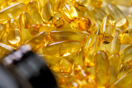 Yellow Omega 3 capsules with a bottle. Scattered natural sea fish supplement. Close up