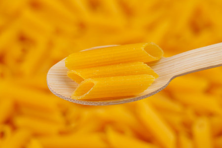 Yellow lentil pasta in a bamboo wooden spoon. Macaroni gluten free