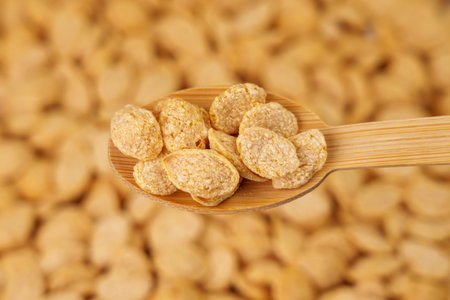 Dry crispy quinoa flakes in the form of seeds in a bamboo spoon close up