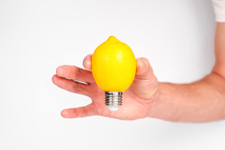 Lemon light bulb in hand on a white background. Creative abstract idea. ingenuity conceptの写真素材