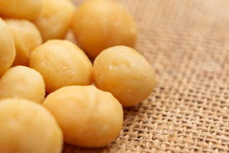 Shelled macadamia nuts on a rough rustic burlap. Nutritious diet food. Macro shotの写真素材