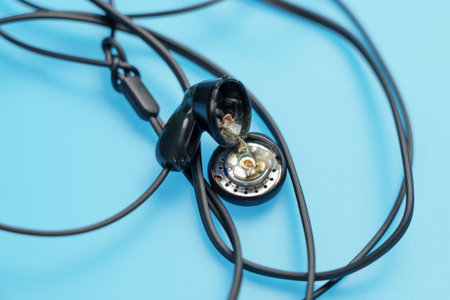 Broken black headset on a blue color background. Macro shotの写真素材