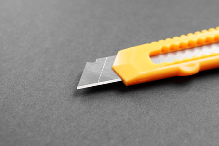 Yellow utility knife on a black cardboard surface. Single cutter for unpacking online orderの写真素材