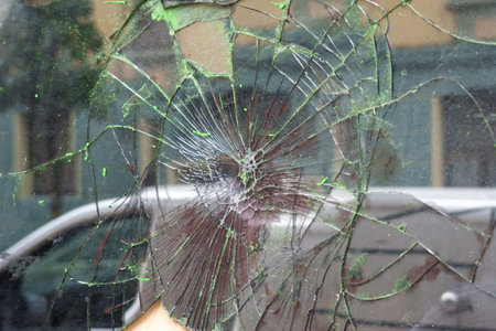 Broken window glass with crack lines on a urban street in reflection close up