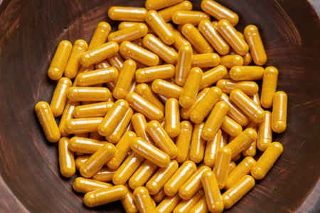Turmeric capsules in wooden bowl. Herbal supplement organic curcumin pills. Antioxidant medicinal ingredient.の写真素材