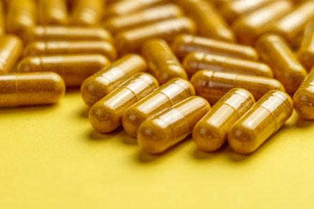 Yellow turmeric (curcuma) supplement capsules on a creative colour background. Herbal medicine pills...