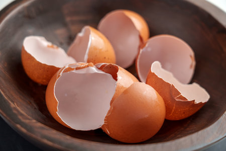 Broken eggshells of chicken brown eggs in wooden kitchen bowl. Organic garbage. Separate waste...