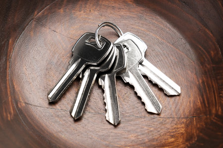 A bunch of metal keys to the apartment door lies in a wooden bowl in close up