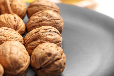 Freshly harvested walnuts gathered from the orchard on a black ceramic plate close upの写真素材