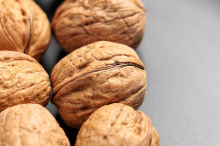 Organically grown whole walnuts in shell nuts on a black ceramic plate. Macro