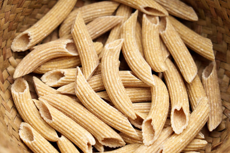 Whole Grain quinoa gluten free uncooked penne pasta in kitchen rustic wicker bowl. Dieting organic ingredients. Macroの写真素材