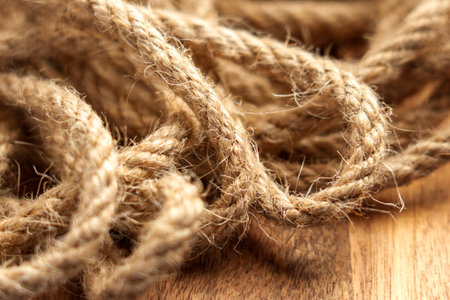 Close-up view of natural jute rope with detailed fibers and texture on a rustic wooden surface....