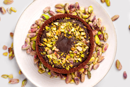 Chocolate cheesecake with pistachio kernels on a kitchen ceramic plate close-up. top viewの写真素材