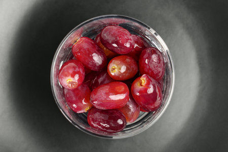 Glass of fresh clean wet red grapes on black ceramic surface. Organic washed berries. Top viewの写真素材