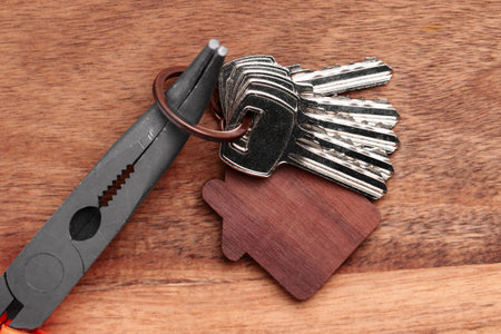 House keys and construction tool pliers on a wooden table. Apartment renovation set