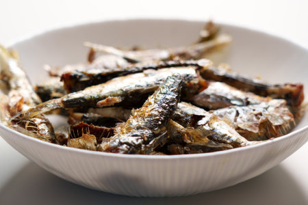 Traditional roasted sardines in white dish on home kitchen table close-upの写真素材