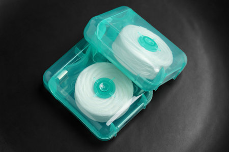 Rolls of white dental floss packaged in green plastic cases on black backgroundの写真素材