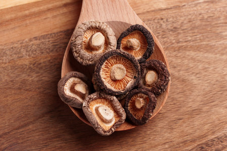 Organic dried dehydrated shriveled shiitake mushrooms in wooden spoon on brown eco friendly table. Top viewの写真素材