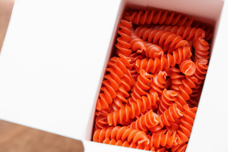 Open paper packet of dry orange lentil pasta close upの写真素材