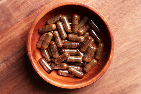 Brown pharmaceutical supplement capsules with herbal extracts in a wooden container. Top viewの写真素材