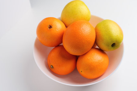 Fresh citrus fruits and green yellow seasonal apples in a white ceramic bowlの写真素材