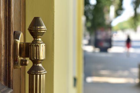 The doorknob on the front door of oak against the backdrop of a sunny day, made in gold and slightly wiped by the hands of those entering.の写真素材