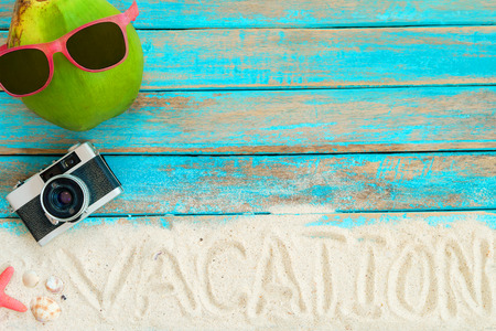 Summer background -   top view of beach sand with coconut, sunglasses, retro camera, starfish and shells on blue wooden background. Summer concept, Vintage retro styles.の写真素材