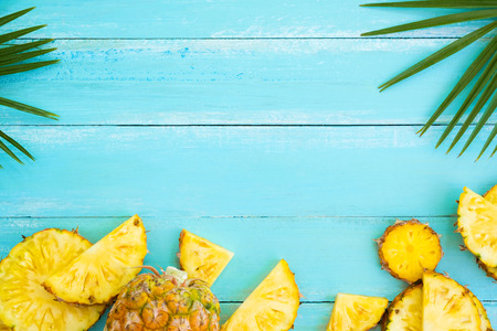 Tropical fruit composition. Pineapple slices and palm leaves  on wood plank blue color. Summer vacation background concept. top view, copy spaceの写真素材