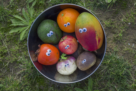 photo of fruits and vegetables with funny eyes in a metal bowlの写真素材