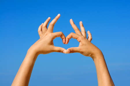 Hand making the sign of Love with the blue sky background の写真素材