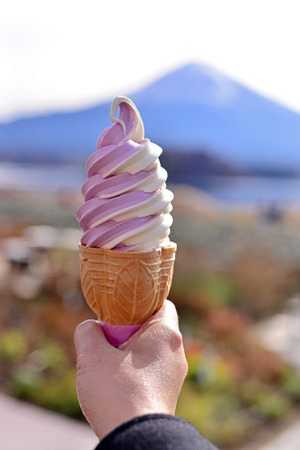 Woman hand holding two tone ice cream in a cone with Mt. Fuji background.の写真素材