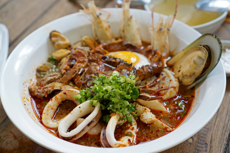 Spicy seafood noodle soup on the wooden table (Thai Foods)の写真素材