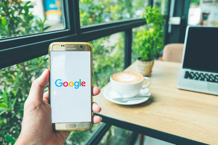 CHIANG MAI, THAILAND - June 26,2018: A Man holds Samsung Galaxy S7 edge Mobile Phone with Google application on the screen in coffee shop.のeditorial素材