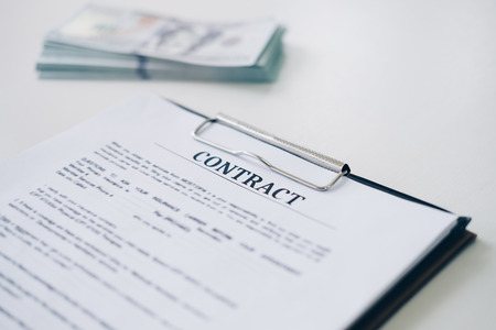 Insurance contract document sheet and business document with money in background in home office,...