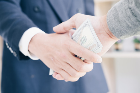 Business man in Suits receiving large amount of US banknotes as a bribe, Corruption in Business concept.の写真素材