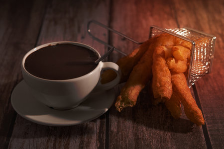 cup of hot chocolate with freshly made churros on wooden background typical spanish breakfast on holidaysの写真素材