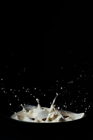 cereal falling into a black plate with milk splashing on a black backgroundの写真素材