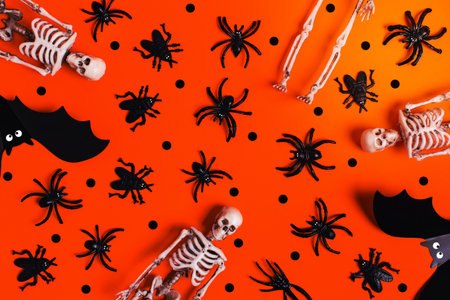 Halloween and decoration concept - orange background with spiders, bats, skeletons. Flat lay, top view. Place for your text.の写真素材