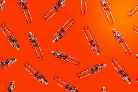 Halloween concept. White skeletons chaotically arranged on orange table. Flat-lay, top view, copy space.の写真素材