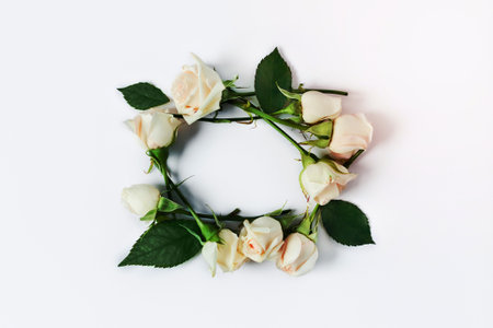 A small frame of white roses and green leaves on a white isolated background.の写真素材