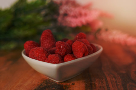 raspberries in a white ceramic bowl on a wooden table