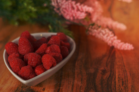 raspberries in a white ceramic bowl on a wooden table
