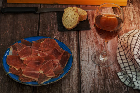 plate of spanish acorn-fed iberian ham in the foreground with bread and wine typical spanish appetizerの写真素材