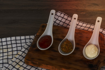 spoons three sauces ketchup mayonnaise mustard white backgroundの写真素材