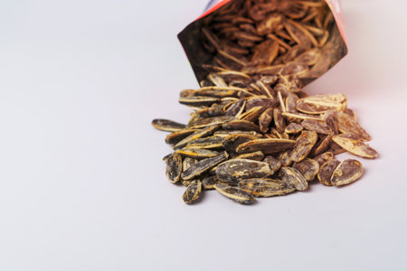 roasted sunflower seeds with salt coming out of their bag on white background and copy spaceの写真素材