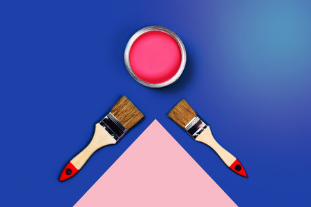 Renovation picture. Blue and pink background with one pain can and two brushes, diagonal composition. Flat lay, top view, copy space.の写真素材