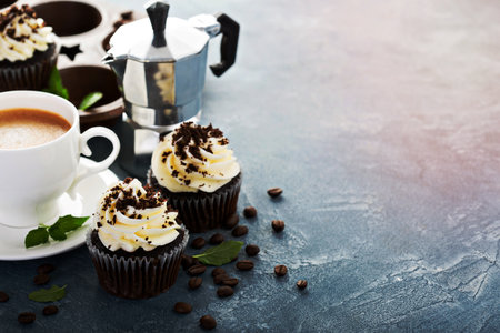 Chocolate cupcakes with vanilla frosting and a cup of coffeeの写真素材